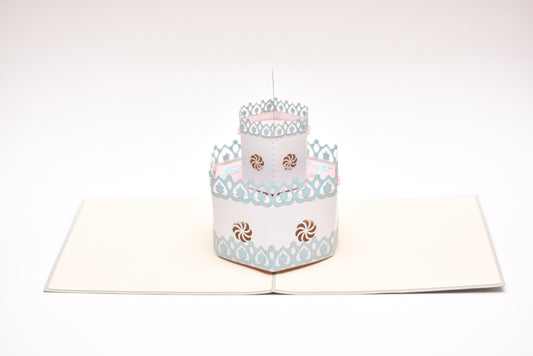 Pop-up card showing two-tiered white birthday cake with blue and pink decor.