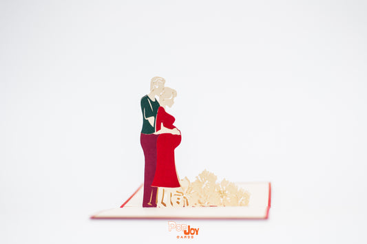 Pop-up card showing expecting couple, with the expecting mum in a red dress and her partner behind her with their arm around her belly