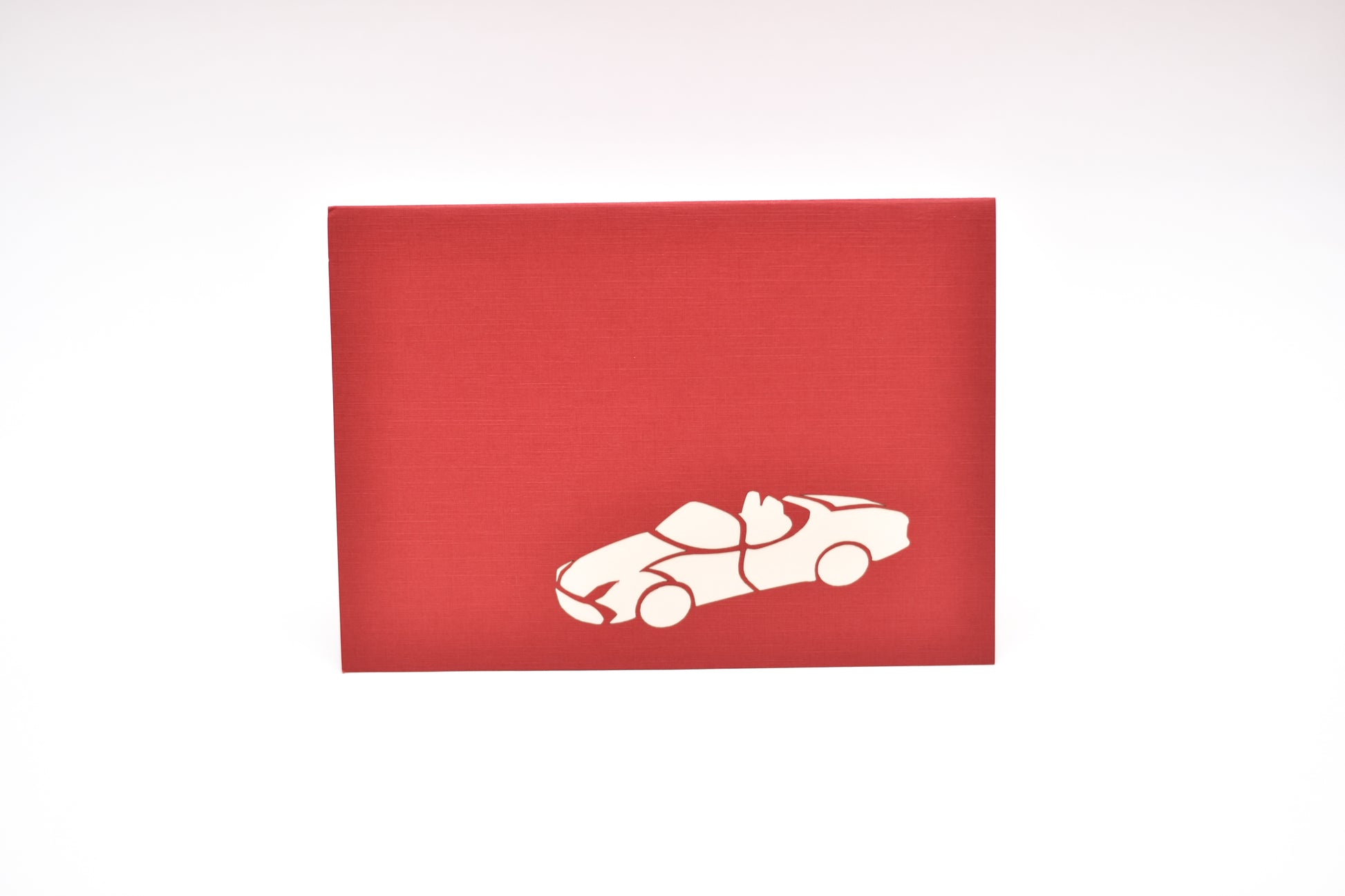 Red card showing silhouette of convertible sports car in white on front cover 