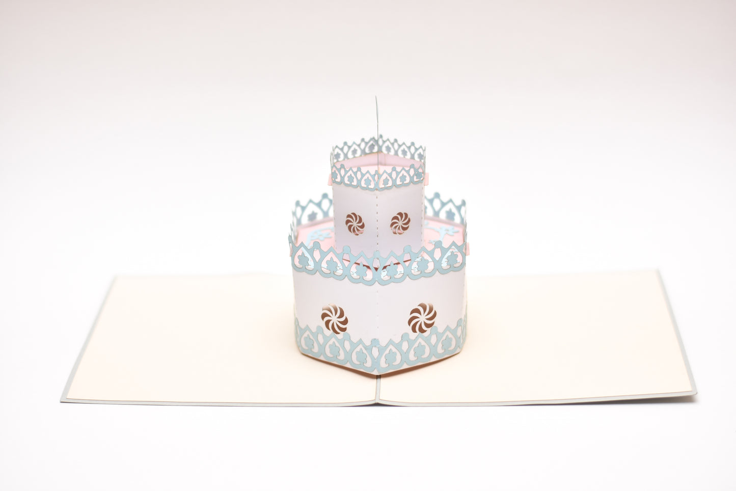 Pop-up card showing two-tiered white birthday cake with blue and pink decor.