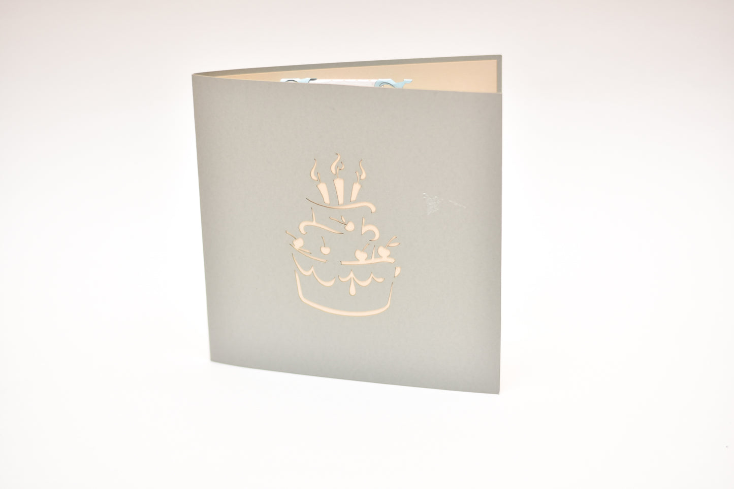 Light grey card with outline of birthday cake with candles on the front cover