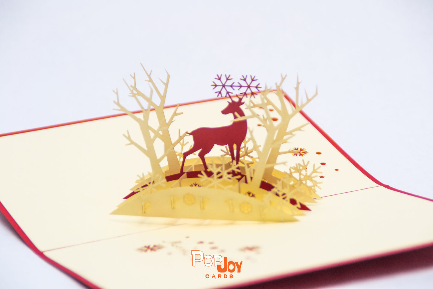 Pop-up card with red reindeer in the middle of light golden forest