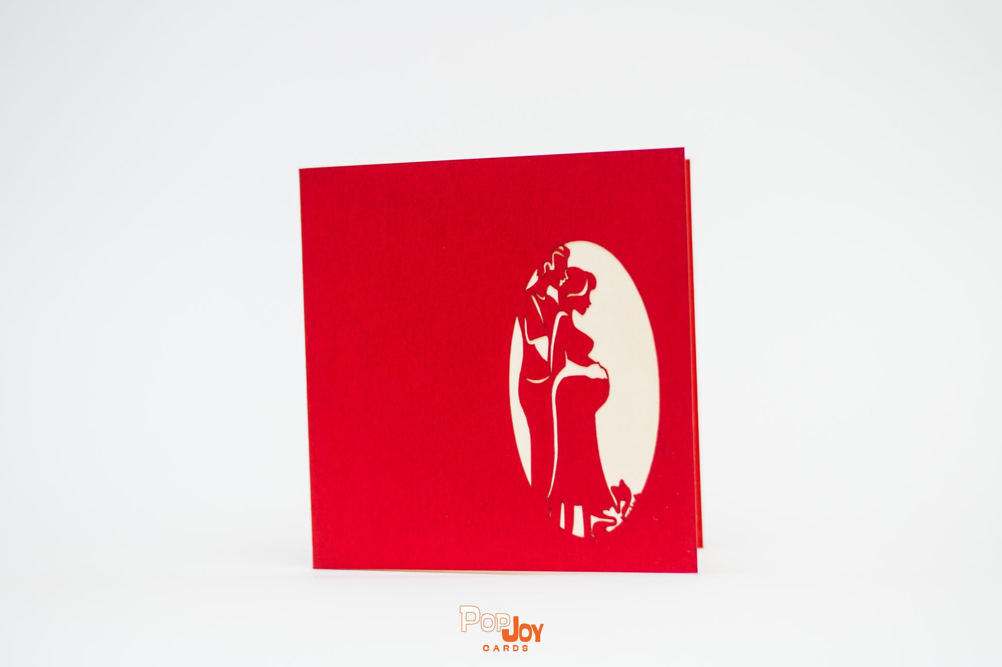 Red card showing silhouette of expecting couple against cream background