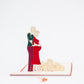 Pop-up card showing expecting couple, with the expecting mum in a red dress and her partner behind her with their arm around her belly