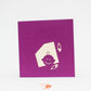 Purple card with silhouette of baby peeking out of window and two diaper pins on front cover