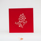 Red card with detailed outline of roses in white on front cover