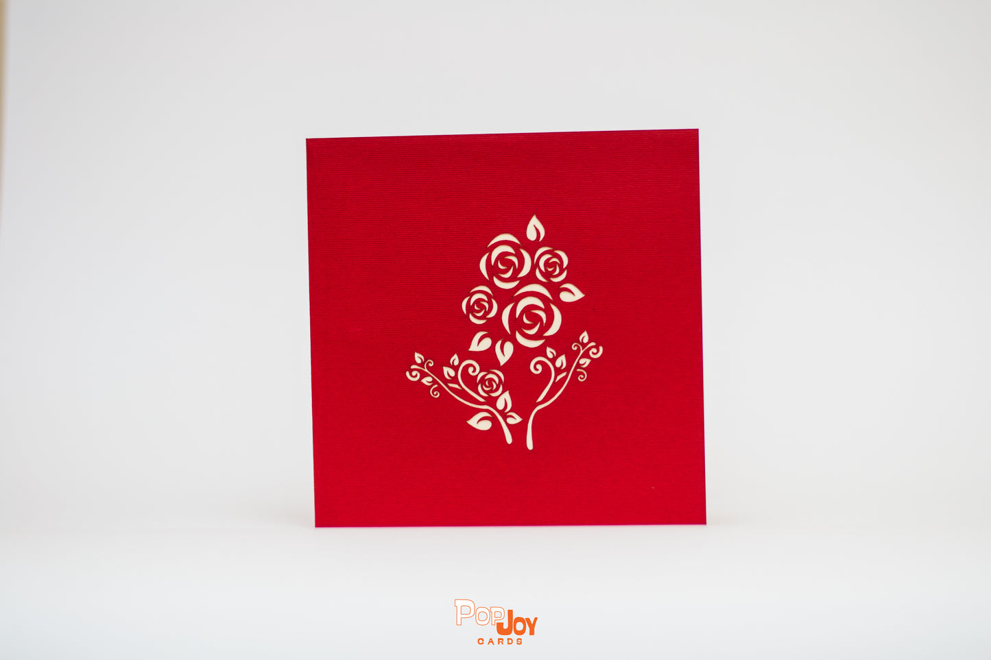 Red card with detailed outline of roses in white on front cover