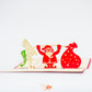 Pop-up card showing Santa lifting weights, with an elf on one side of the barbell and a bag of toys on the other side