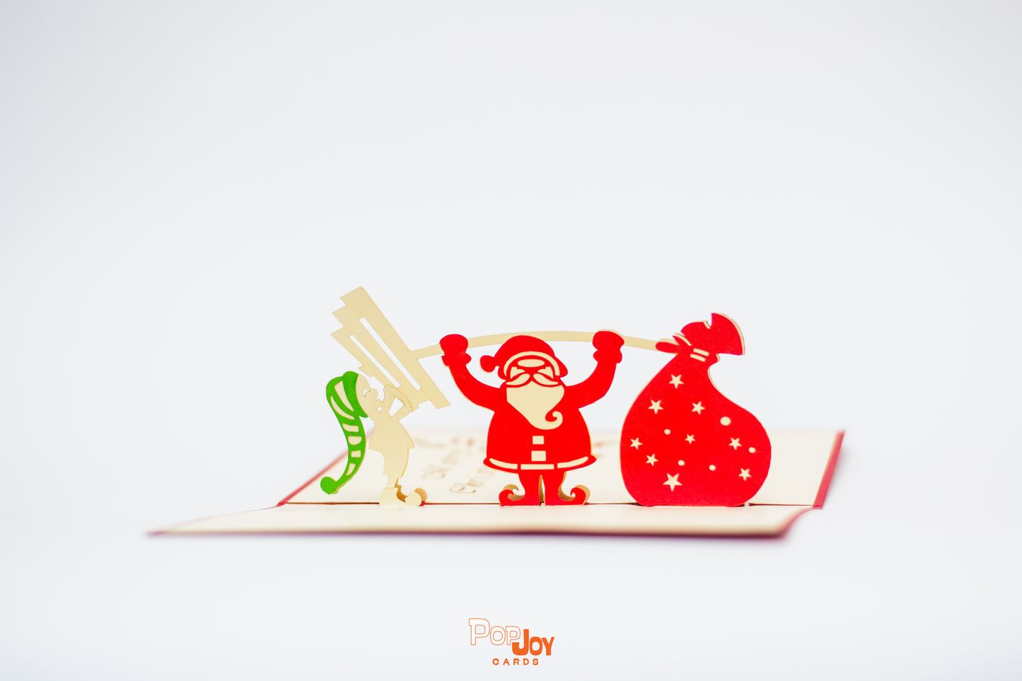 Pop-up card showing Santa lifting weights, with an elf on one side of the barbell and a bag of toys on the other side