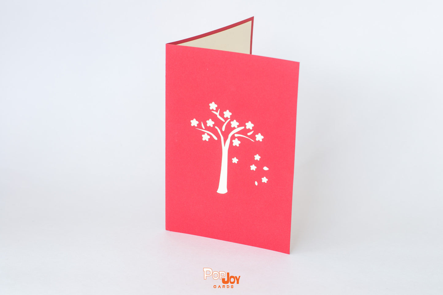 Red card with flowering tree in white on front cover