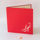 Red card featuring outline of women's heeled shoe in bottom right corner of front cover