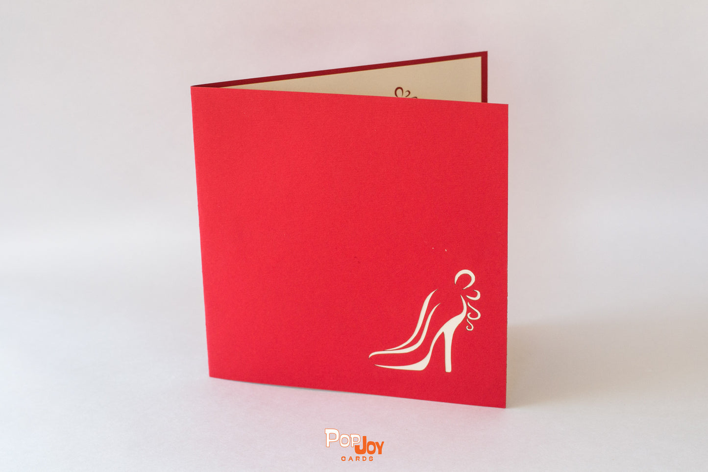 Red card featuring outline of women's heeled shoe in bottom right corner of front cover